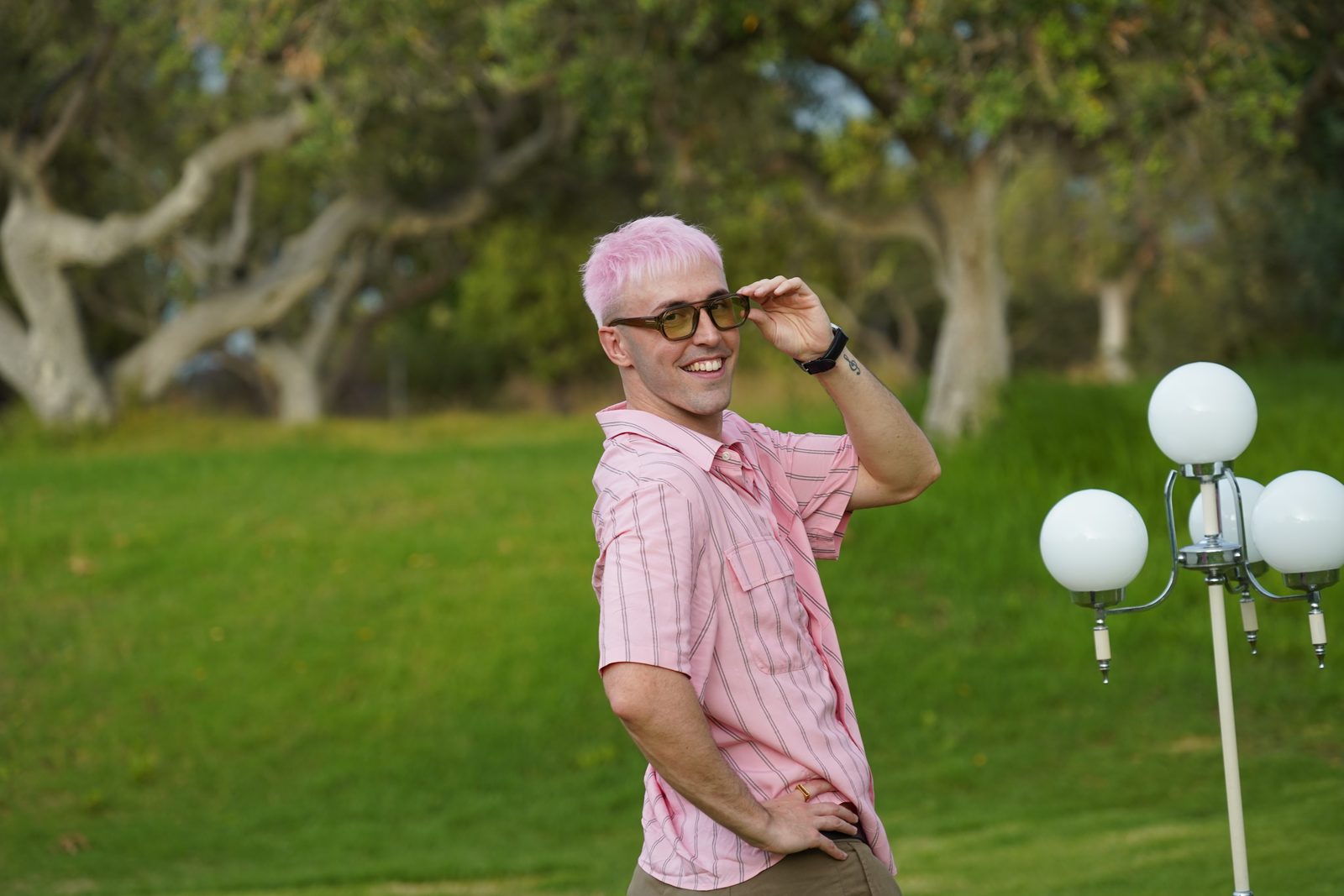 Markos amb camisa rosa, posant amb la mà a les ulleres